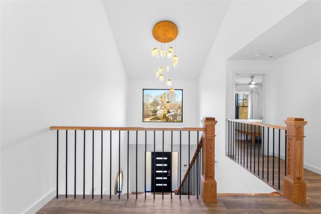 Hall with a notable chandelier, lofted ceiling, an upstairs landing, wood finished floors, and baseboards | Image 7