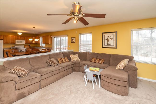 Living area featuring baseboards, light colored carpet, and ceiling fan with notable chandelier | Image 14