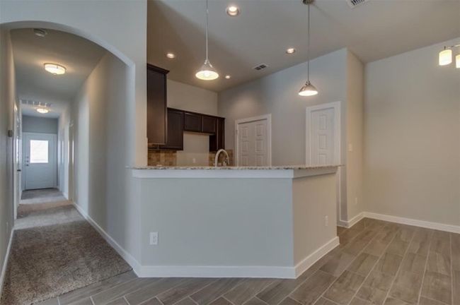 Kitchen with dark brown cabinets, wood finish floors, arched walkways, light stone counters, and recessed lighting | Image 10