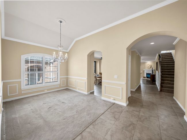 Unfurnished dining area featuring carpet, vaulted ceiling, crown molding, a fireplace, and a decorative wall | Image 5