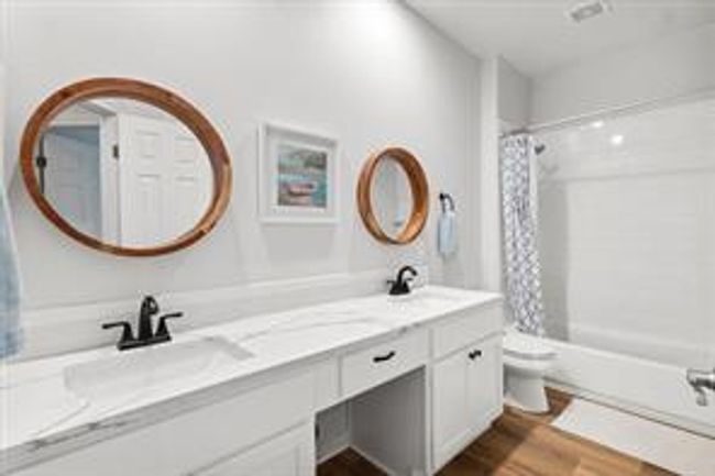 Full bath with double vanity, toilet, wood finished floors, and a sink | Image 16