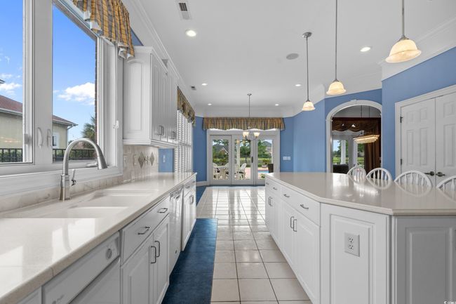 Kitchen featuring dishwasher, french doors, white cabinets, light countertops, and light tile patterned floors | Image 13