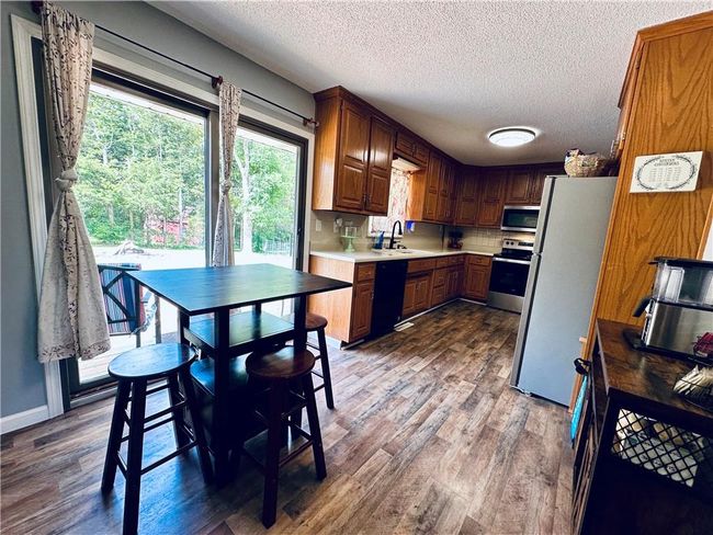 Kitchen with appliances with stainless steel finishes, a sink, dark wood-style flooring, a textured ceiling, and light countertops | Image 10