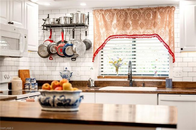 Kitchen featuring white appliances, tasteful backsplash, and white cabinetry | Image 13