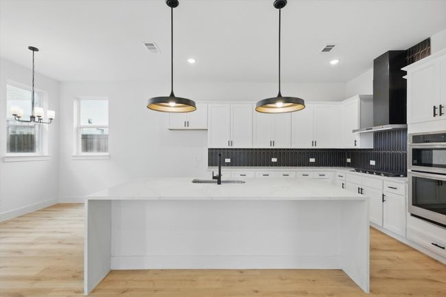 Kitchen with a sink, wall chimney range hood, stainless steel appliances, a chandelier, and tasteful backsplash | Image 19
