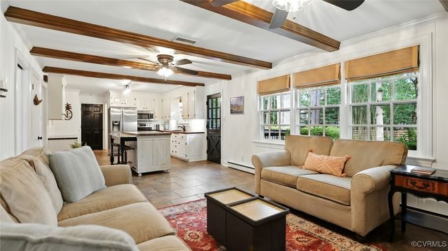 Living area with ceiling fan, a baseboard heating unit, plenty of natural light, beamed ceiling, and crown molding | Image 33