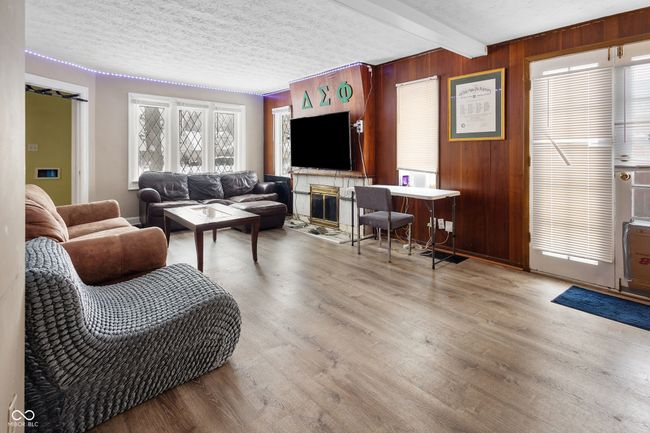 living area featuring beamed ceiling, wood finished floors, and wood walls | Image 16
