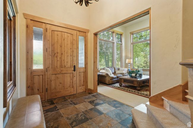 Foyer entrance featuring stone tile flooring, healthy amount of natural light, and a chandelier | Image 20
