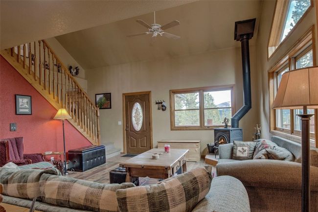 Living room with a wood stove, high vaulted ceiling, stairs, a ceiling fan, and wood finished floors | Image 11