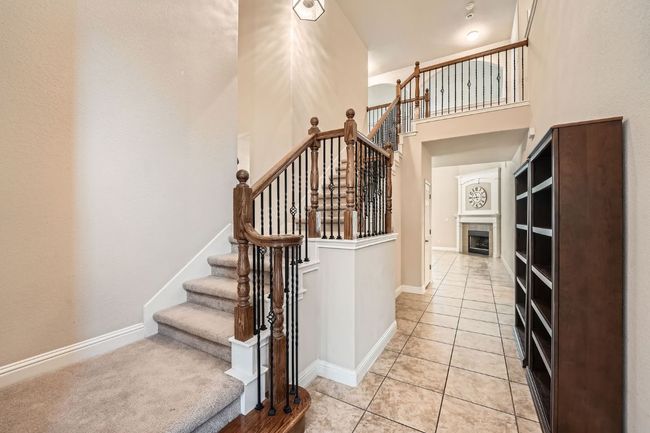 Stairs featuring a high ceiling, a tiled fireplace, baseboards, and tile patterned floors | Image 23
