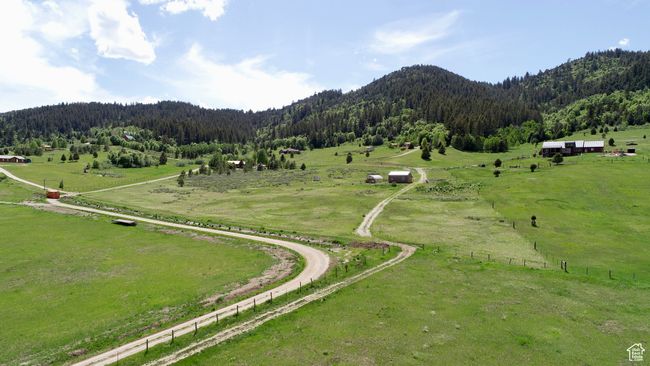 Aerial view of sparsely populated area featuring a forest, a mountain backdrop, and agricultural land | Image 9