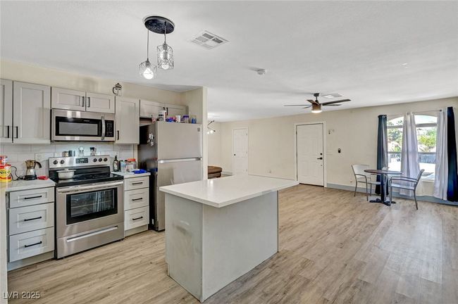 Kitchen featuring appliances with stainless steel finishes, light countertops, decorative backsplash, light wood-style floors, and ceiling fan | Image 14