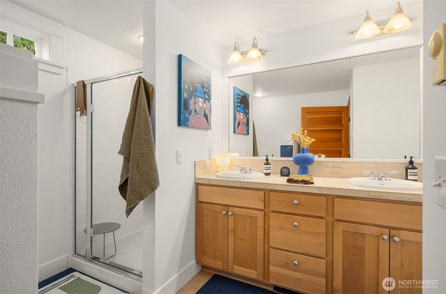 The primary bath with shower, tub, dual vanity with maple cabinet and travertine tile surface. The home also has a second full bathroom. | Image 17