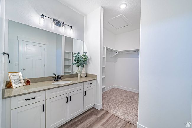 Bathroom featuring a textured ceiling, vanity, a spacious closet, wood finished floors, and baseboards | Image 9
