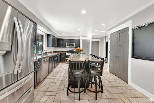 Kitchen featuring light stone counters, a center island, sink, a kitchen bar, and stainless steel appliances | Image 11