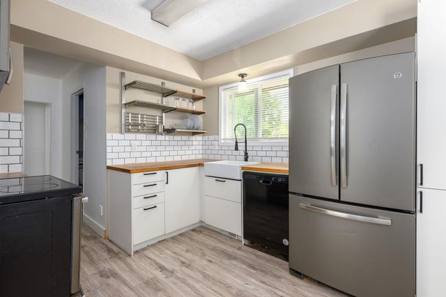 Kitchen with freestanding refrigerator, butcher block countertops, dishwasher, and a sink | Image 14