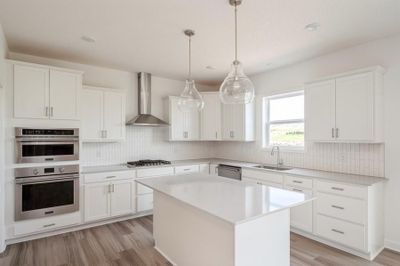 Photo is of the actual home. Welcome to the Lewis! This spacious gourmet kitchen features a large center island, quartz countertops, LVP floors, stainless appliances and more. | Image 3