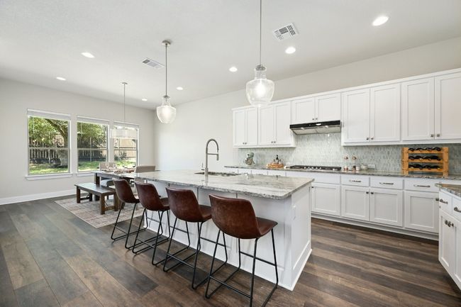The kitchen is a chef's dream with stainless steel appliances, granite countertops, ample cabinetry, and a large island with seating. | Image 10