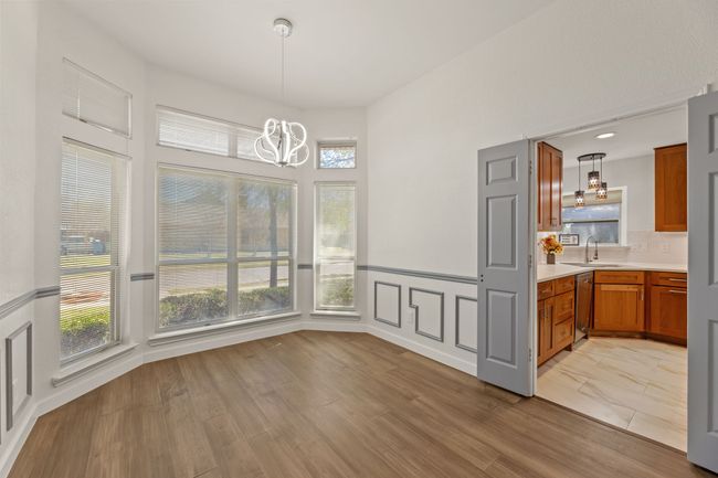 Unfurnished dining area featuring light wood-type flooring, an inviting chandelier, a sink, a decorative wall, and wainscoting | Image 5