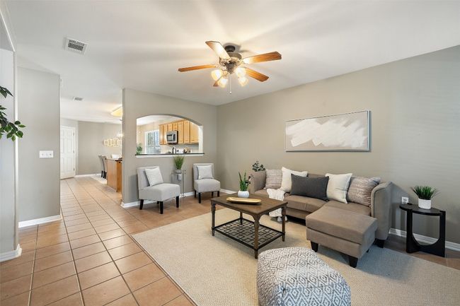 Living area with a ceiling fan, light tile patterned floors, and baseboards | Image 14