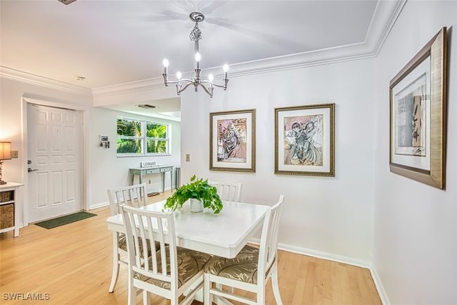 Dining space with ornamental molding, light wood-style floors, and a chandelier | Image 8