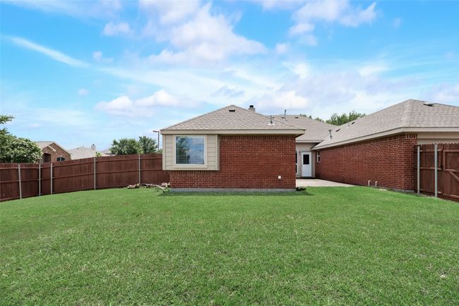 Rear view of property featuring brick siding, roof with shingles, and a patio area | Image 21