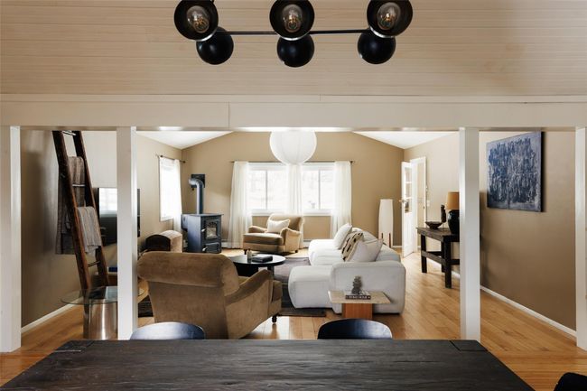 Living room with light wood-type flooring, vaulted ceiling, and a wood stove | Image 9