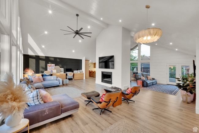 Living area with high vaulted ceiling, a fireplace, light wood-type flooring, recessed lighting, and a ceiling fan | Image 14