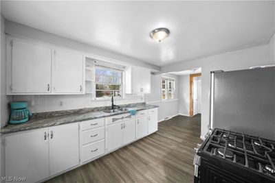 Kitchen with white cabinets, stainless steel fridge, and dark wood-type flooring | Image 3