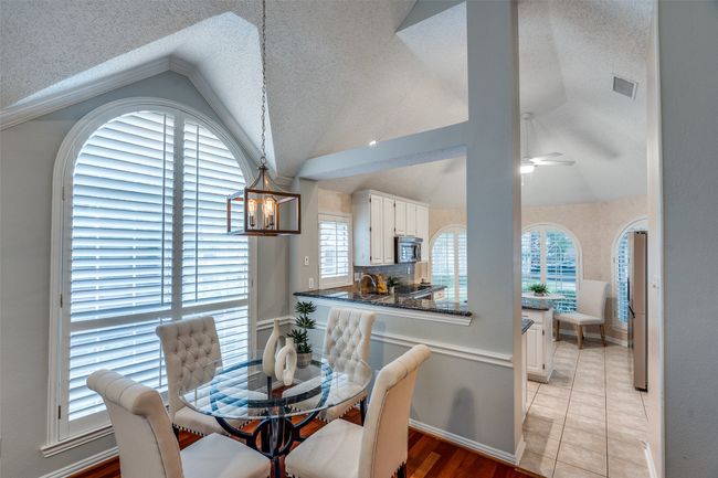 Dining room featuring lofted ceiling, healthy amount of natural light, a textured ceiling, a ceiling fan, and baseboards | Image 6