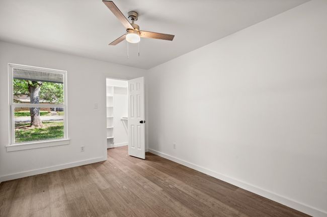 Unfurnished bedroom featuring wood finished floors, a walk in closet, a ceiling fan, and a closet | Image 17