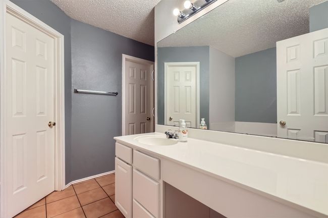 Bathroom featuring tile patterned flooring, a textured ceiling, and vanity | Image 16