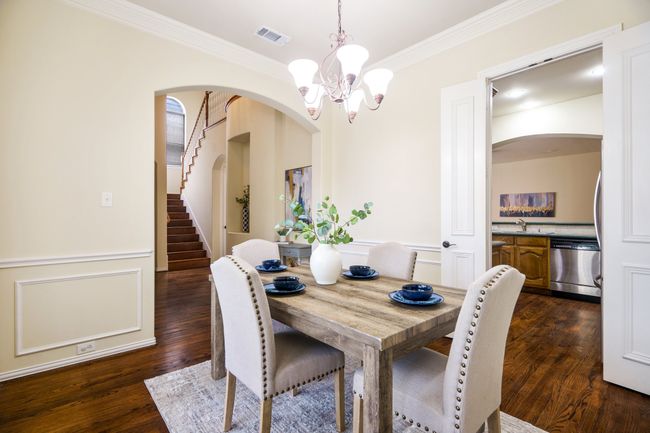 Dining room features a chandelier, crown molding, arched walkways, and wood floors | Image 4