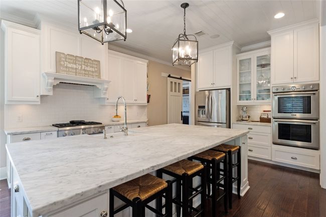 Kitchen with stainless steel appliances, a chandelier, recessed lighting, white cabinetry, and ornamental molding | Image 7