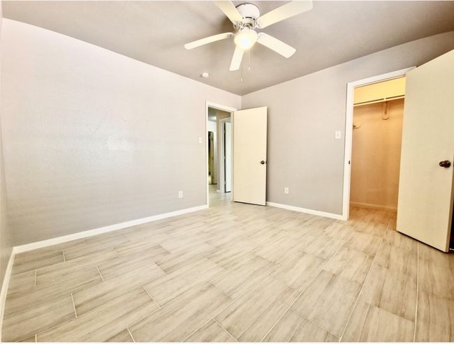 Unfurnished bedroom featuring a spacious closet, light wood-style floors, a ceiling fan, and a closet | Image 13