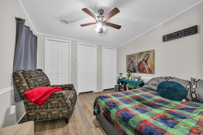 Bedroom featuring wood finished floors, crown molding, a textured ceiling, and ceiling fan | Image 14