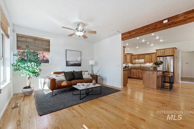 Living room featuring light wood-style floors, a ceiling fan, beam ceiling, and a textured ceiling | Image 16