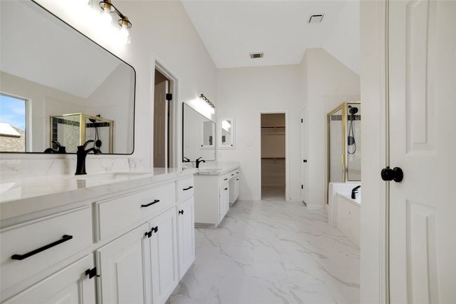 Bathroom featuring a stall shower, vanity, marble look tiles, a garden tub, and a spacious closet | Image 20