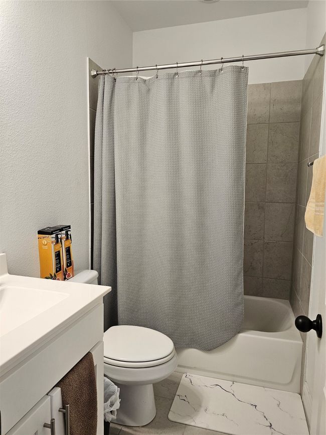 Full bath featuring vanity, shower / bath combination with curtain, and a textured wall | Image 14