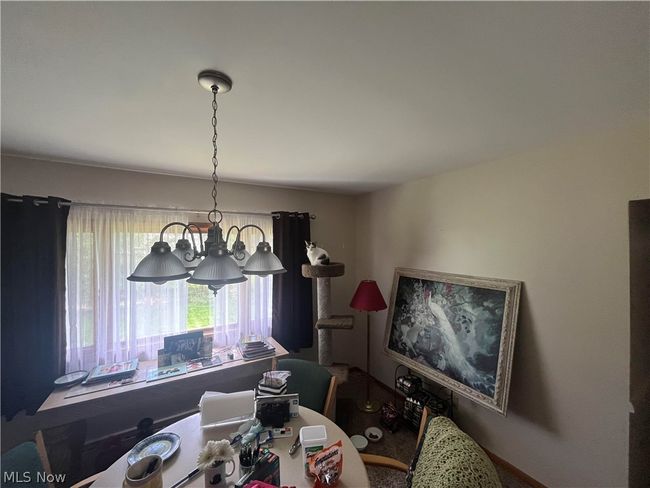 Living room with a baseboard heating unit, carpet floors, and a brick fireplace | Image 5