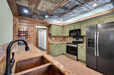 Kitchen with green cabinetry, appliances with stainless steel finishes, and copper sink | Image 1