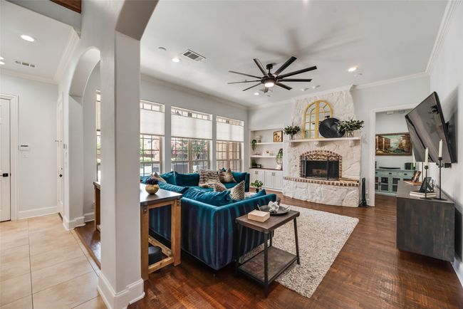 Living room with ceiling fan, arched walkways, a stone fireplace, ornamental molding, and wood finished floors | Image 14