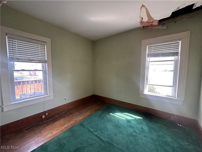 Carpeted spare room with baseboards, wood finished floors, visible vents, and a healthy amount of sunlight | Image 9