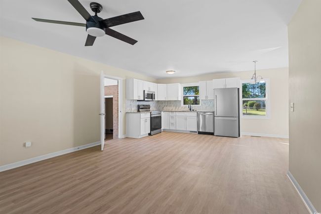 Kitchen with appliances with stainless steel finishes, light wood finished floors, backsplash, white cabinets, and light countertops | Image 15