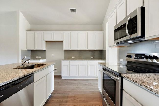 Kitchen with stainless steel appliances, a sink, and white cabinetry | Image 8