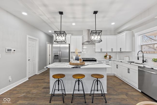 kitchen with quartz counter-tops, soft close cabinets, decorative backsplash, chandeliers, recessed lighting, stainless steel appliances, huge island and a farmers sink | Image 9