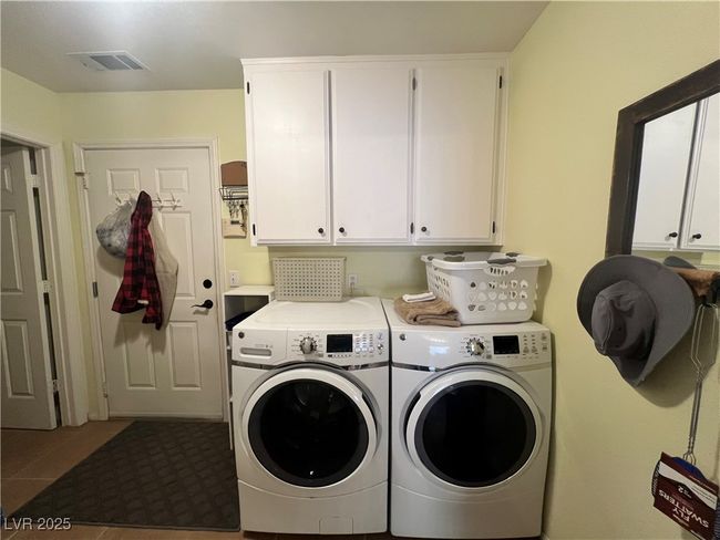 Washroom featuring cabinet space, washer and clothes dryer, and tile patterned floors | Image 23