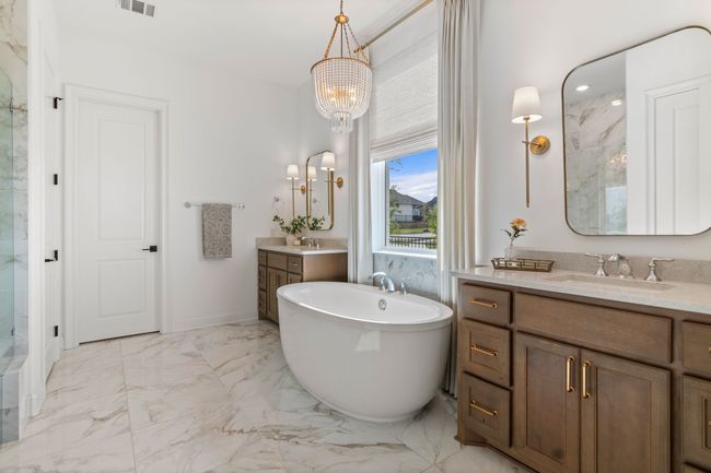 Bathroom featuring light marble finish flooring, a soaking tub, two vanities, a marble finish shower, and a chandelier | Image 23