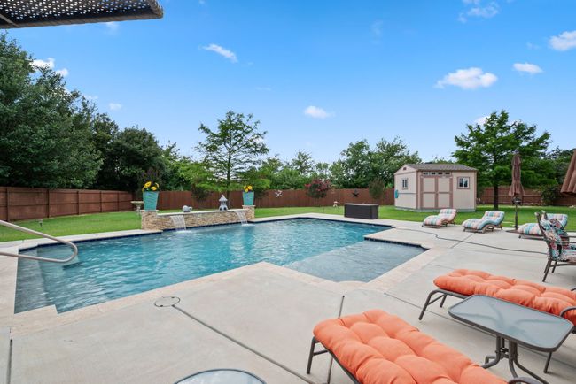 View of pool with a fenced backyard, a patio, and a storage shed | Image 7