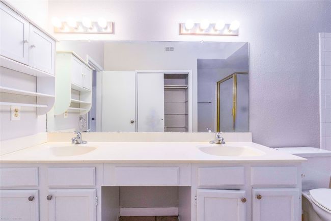 Primary bathroom features large double vanity with sit down makeup vanity in between | Image 16